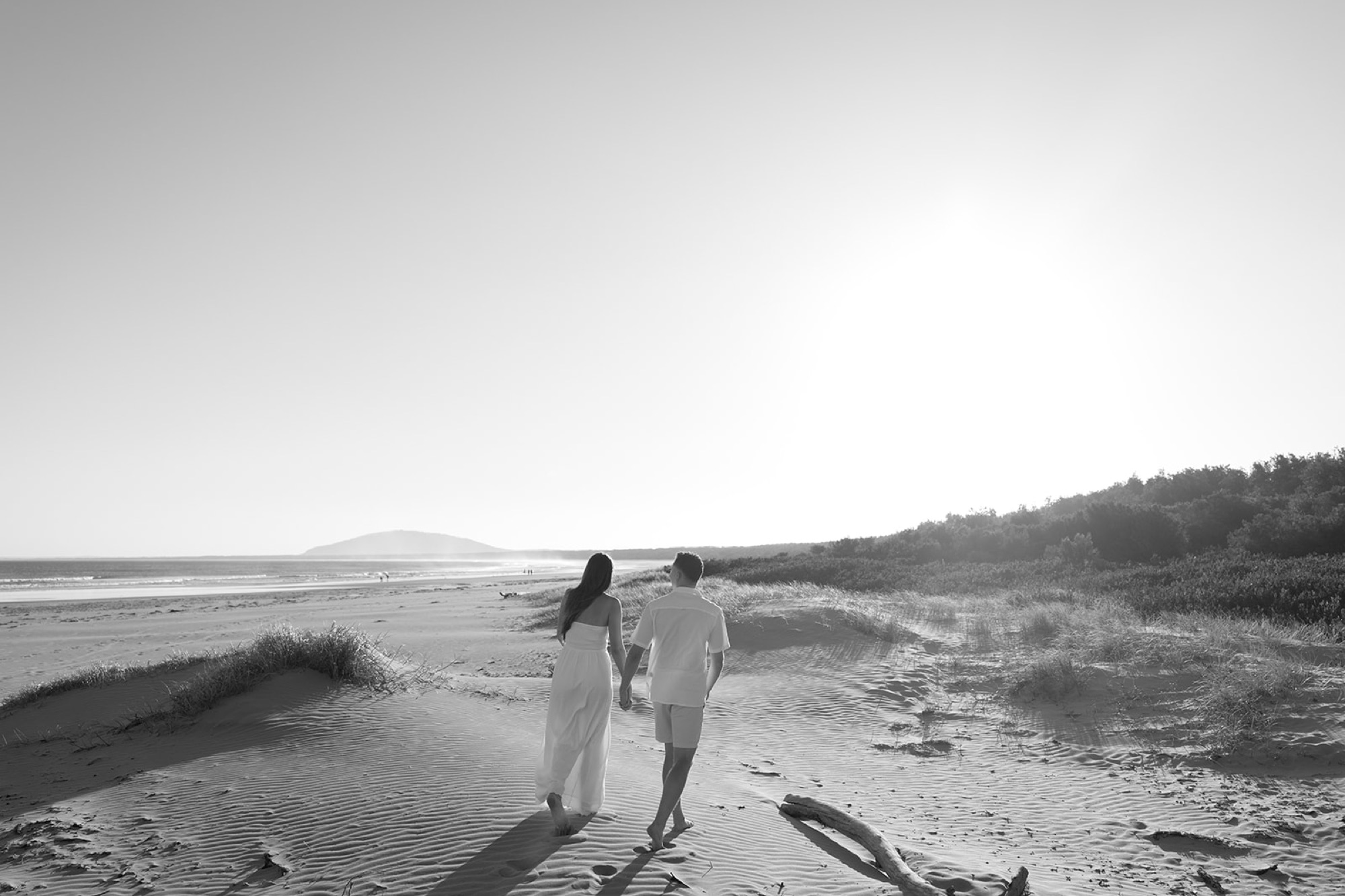 Black and white photo of a couple walking together through the dunes