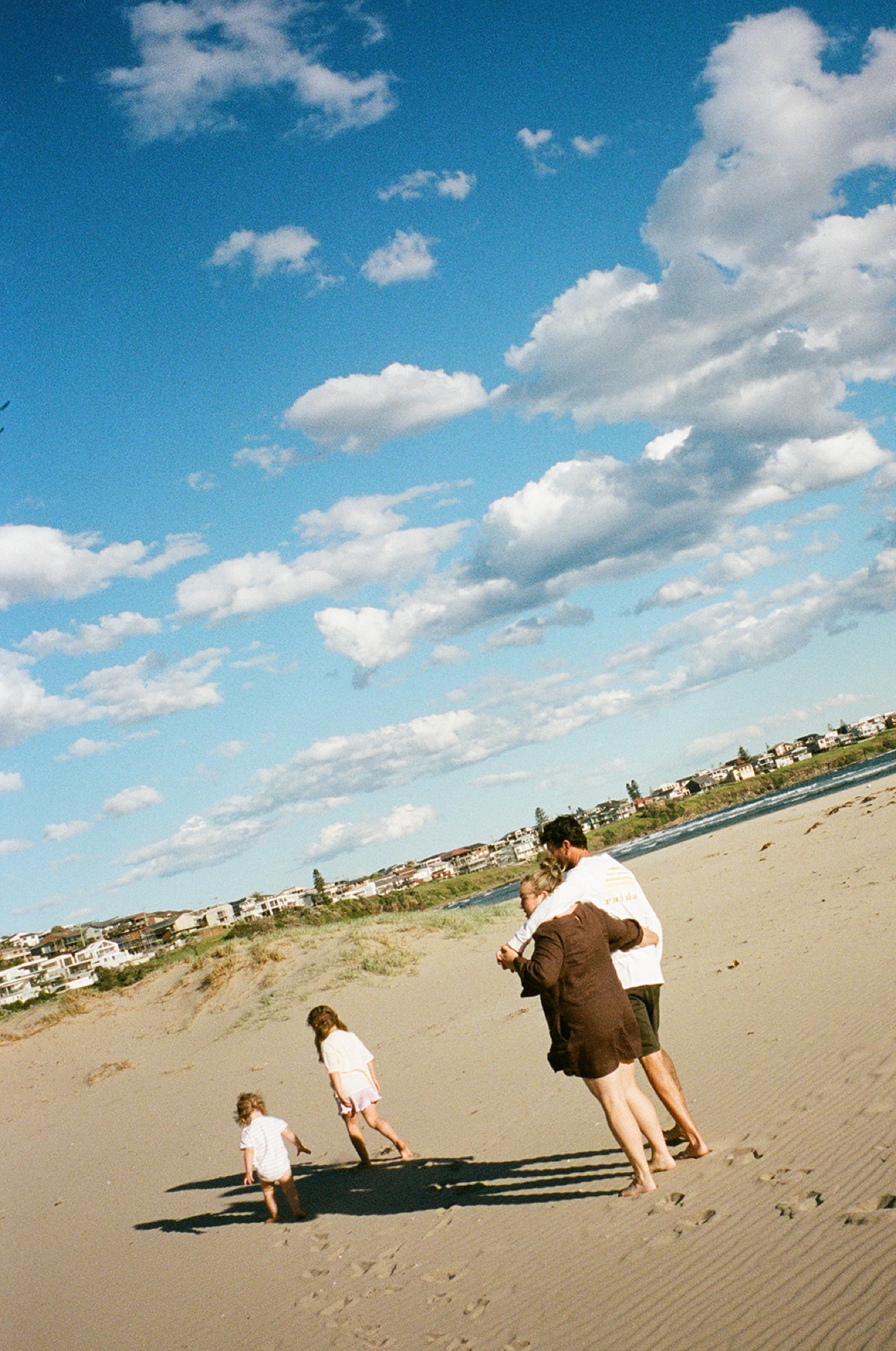 Parents and two little ones on a sand dune under a bright blue sky