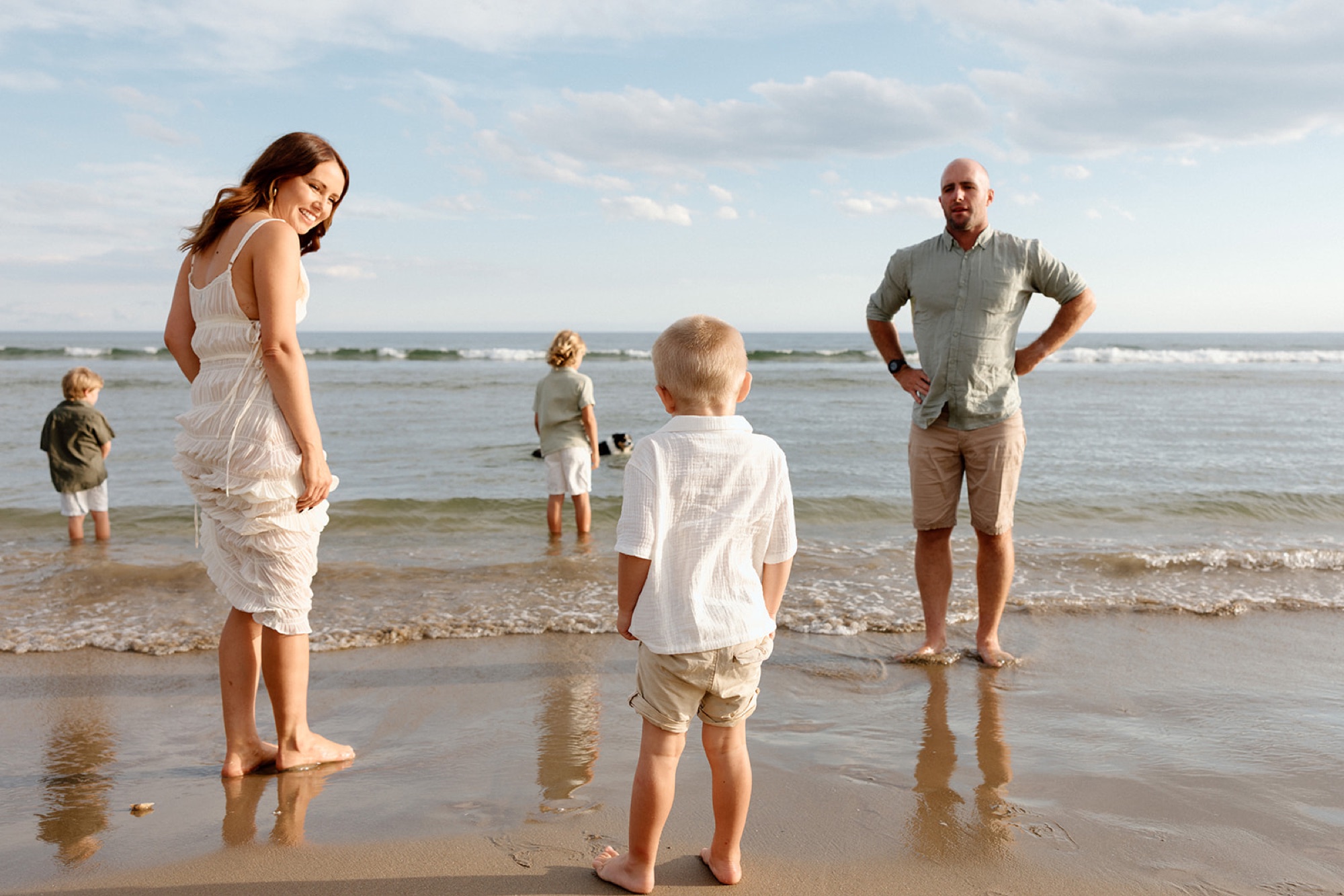 A mum laughing with her boys at the water's edge while dad looks on